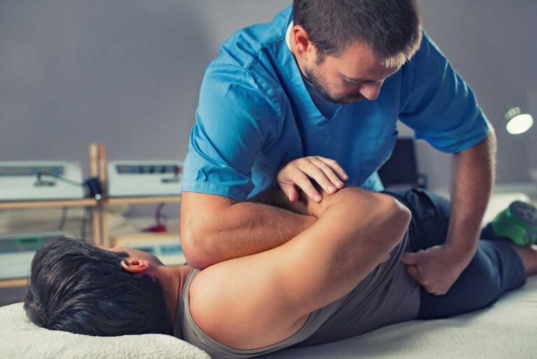 A chiropractor and physical therapist discussing a patient's spine model and treatment plan together in a clinic setting.