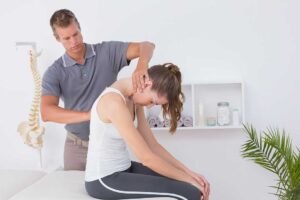 Person gently touching the jaw while seated with relaxed shoulders and visible neck muscles